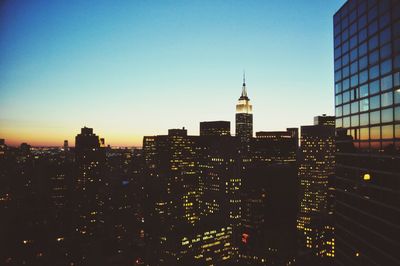 View of city lit up against clear sky