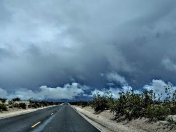 Road passing through landscape against cloudy sky