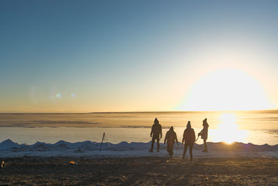 People on beach against sky during sunset