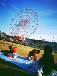 People riding bicycle at amusement park against sky