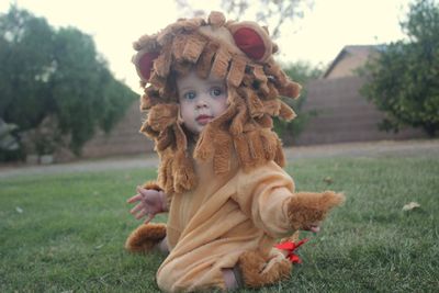 Portrait of cute baby girl wearing costume kneeling on land