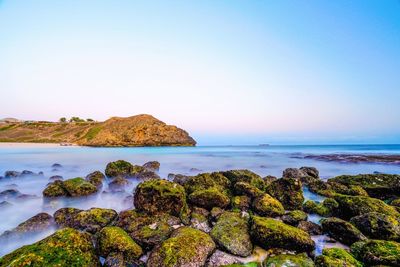 Scenic view of rocks on beach against clear sky