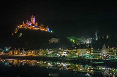 Illuminated buildings reflecting on lake in river at night