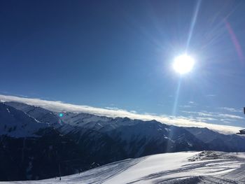 Scenic view of snowcapped mountains against bright sun