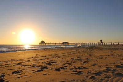 Scenic view of beach against clear sky during sunset