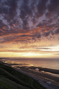 Scenic view of sea against dramatic sky during sunset