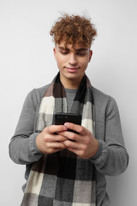 Young woman using mobile phone while standing against white background