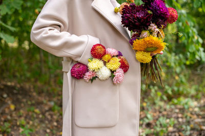 Composition of autumn flowers in the pocket of a beige coat