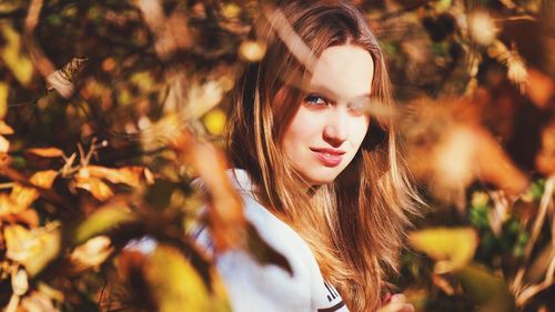 Portrait of young woman amidst trees during autumn