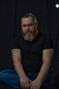 Portrait of senior man sitting against black background