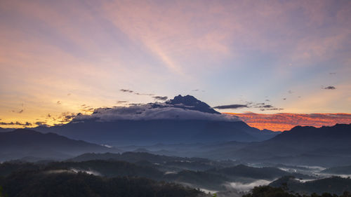 Scenic view of mountains against dramatic sky during sunset