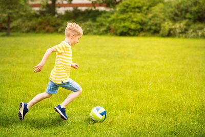 Full length of boy playing with ball on grass