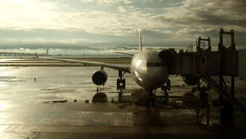 Airplane at airport runway against sky