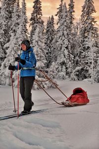 Full length of woman skiing with sled on snow covered land