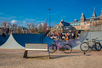 Bicycle parked by building in city against sky