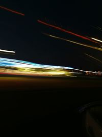 Light trails on road against sky at night