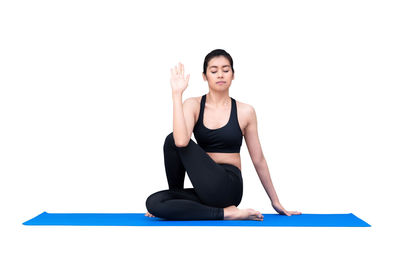 Young woman with arms raised against white background