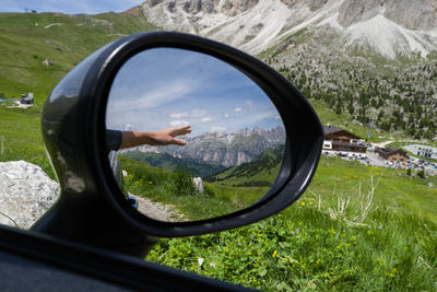 Reflection of the hand with mountain backdrop in the car mirror