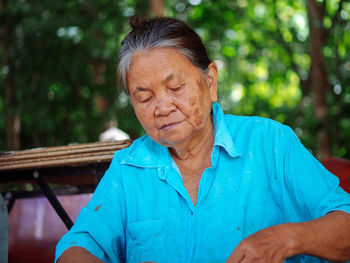 Portrait of senior man looking away while sitting outdoors