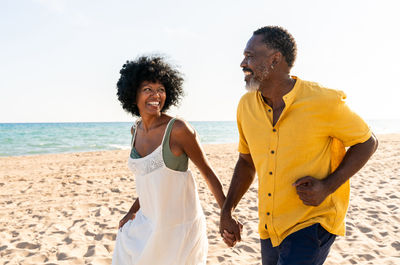 Side view of couple standing at beach