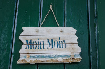 Close-up of old wooden signboard hanging from door