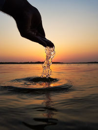Reflection of man in sea against sky during sunset