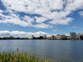 Buildings by lake against sky in city