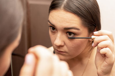 Close-up of young woman applying mascara