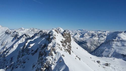 Scenic view of snowcapped mountains against blue sky