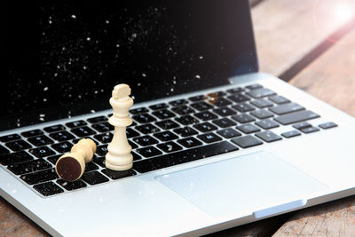 Close-up of chess piece on laptop at table