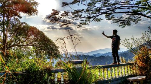 Man photographing with arms outstretched standing on landscape