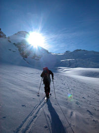 Man skiing on snowcapped mountain against sky during winter