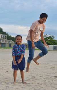 Full length of siblings on beach