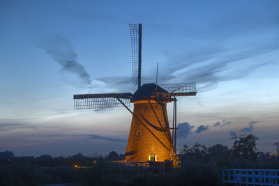 Traditional windmill against sky during sunset