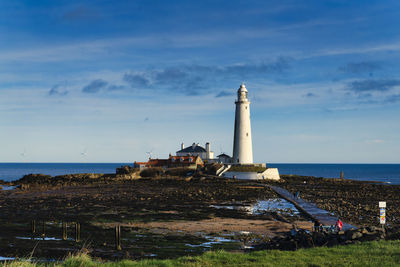 Lighthouse by sea against sky