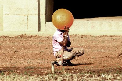 Construction worker crouching with shovel and bowl on field