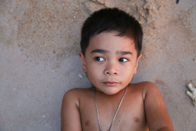 High angle view of shirtless boy lying on sand at beach