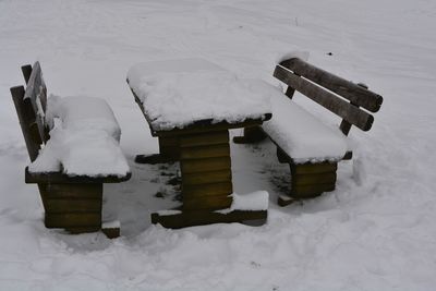 High angle view of snow covered bench on field