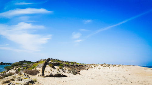 Sand dune by sea against blue sky