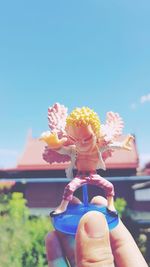 Midsection of person holding flowering plant against sky