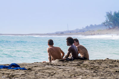 Rear view of two people sitting on beach