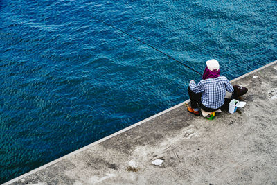 Rear view full length of man fishing by sea