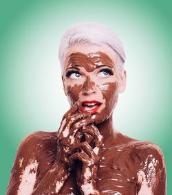 Close-up of shirtless female model covered with chocolate against green background