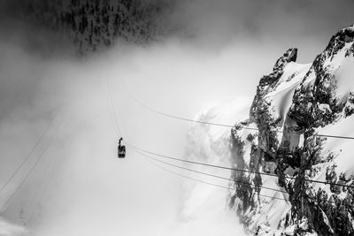 Overhead cable car by snowcapped mountain