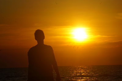 Rear view of silhouette man against sea during sunset