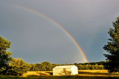 Scenic view of rainbow over field against sky