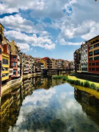 Buildings by river against sky in city