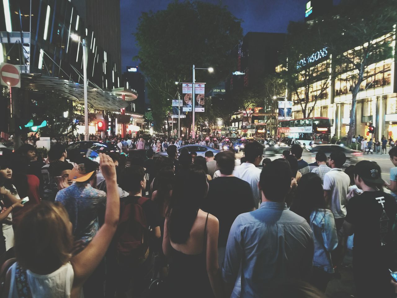 large group of people, building exterior, crowd, men, person, city, lifestyles, street, illuminated, leisure activity, architecture, built structure, city life, night, mixed age range, outdoors, city street, togetherness, sitting