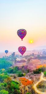 Hot air balloon flying over landscape against sky during sunset