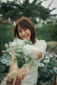 Portrait of young woman standing against plants